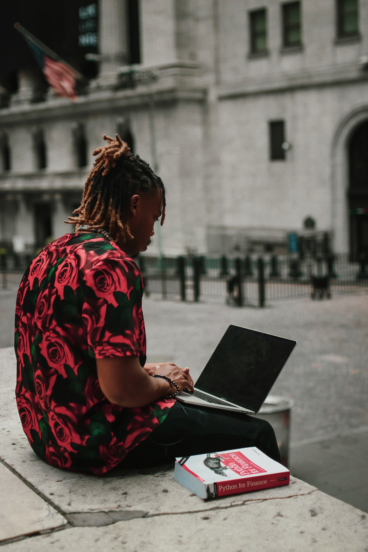 Antoine on the curb in front of the New York Stock Exchange with a laptop and Python for Finance