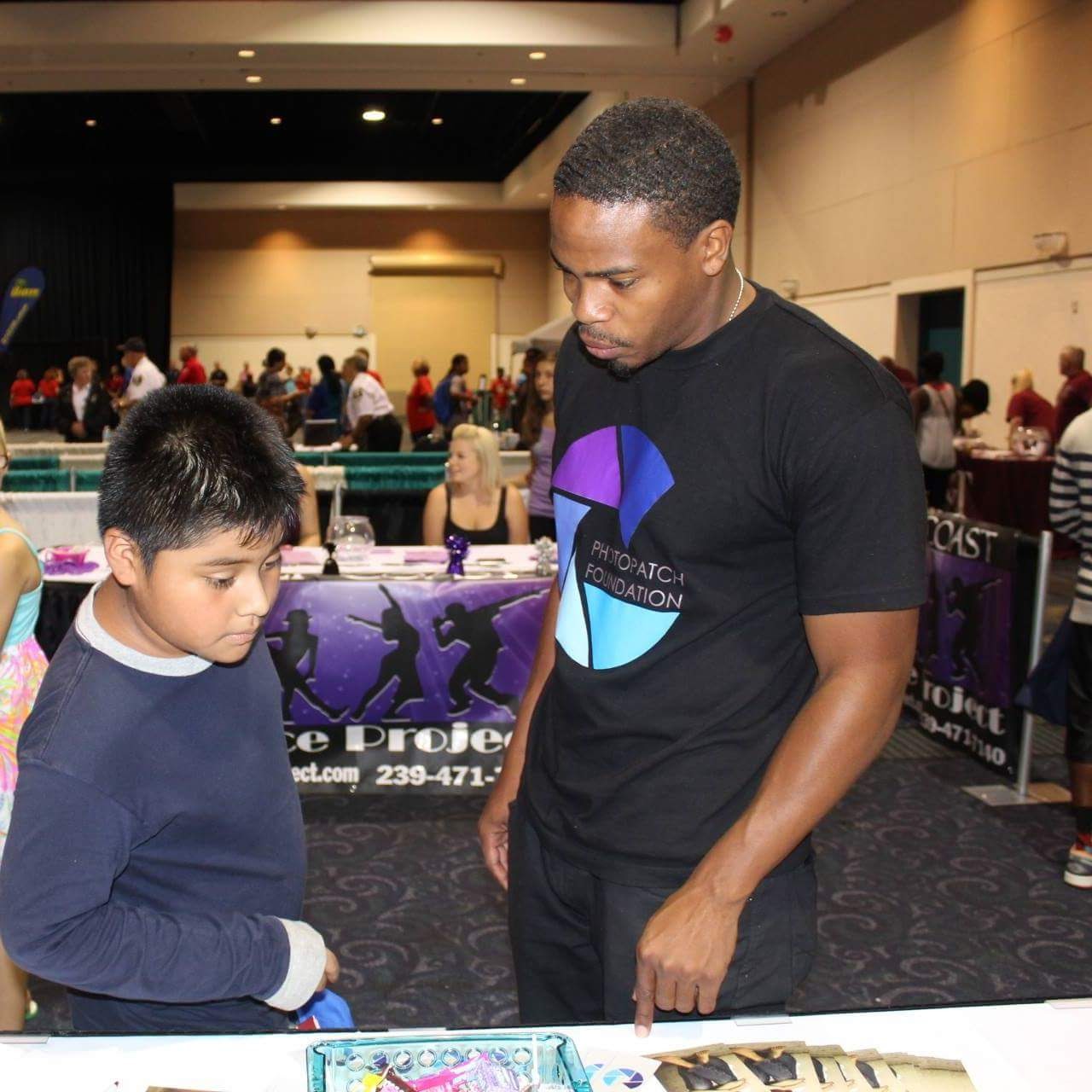 Antoine at a Photo Patch Foundation table, working with a child