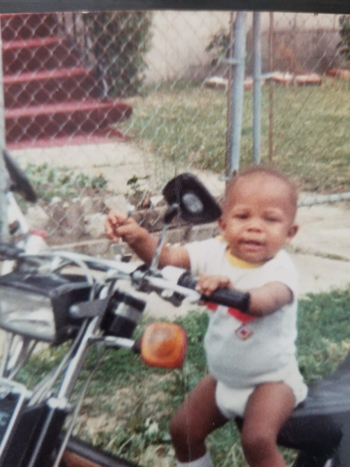 Antoine as a baby on a motorcycle in the backyard